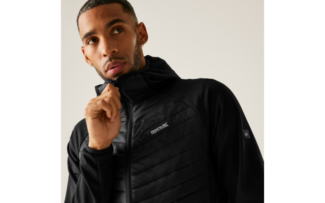 Oberkörper einer Person mit kurzem Haar und Ohrring, die am Reißverschluss einer schwarzen gestepp-ten Jacke zieht; Markenlogo auf der Brust sichtbar