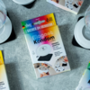 Verpackung eines Magnet-Kondoms auf grauem Untergrund, mit weißen Tassen und Tellern im Hintergrund