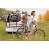 Un homme et une femme sont debout avec deux vélos à côté d'une camionnette blanche sur une prairie, arbres d'automne en arrière-plan