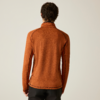Personne de dos portant un haut orange à manches longues avec coutures visibles, pantalon foncé, fond uni clair