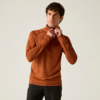 Personne aux cheveux courts et foncés porte un haut à manches longues orange avec une demi-fermeture éclair et un pantalon foncé, tire sur la fermeture; fond uni clair