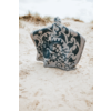 Objet à motif bleu et blanc à sommet arrondi posé sur du sable clair, dunes avec herbe sèche et ciel nuageux en arrière-plan