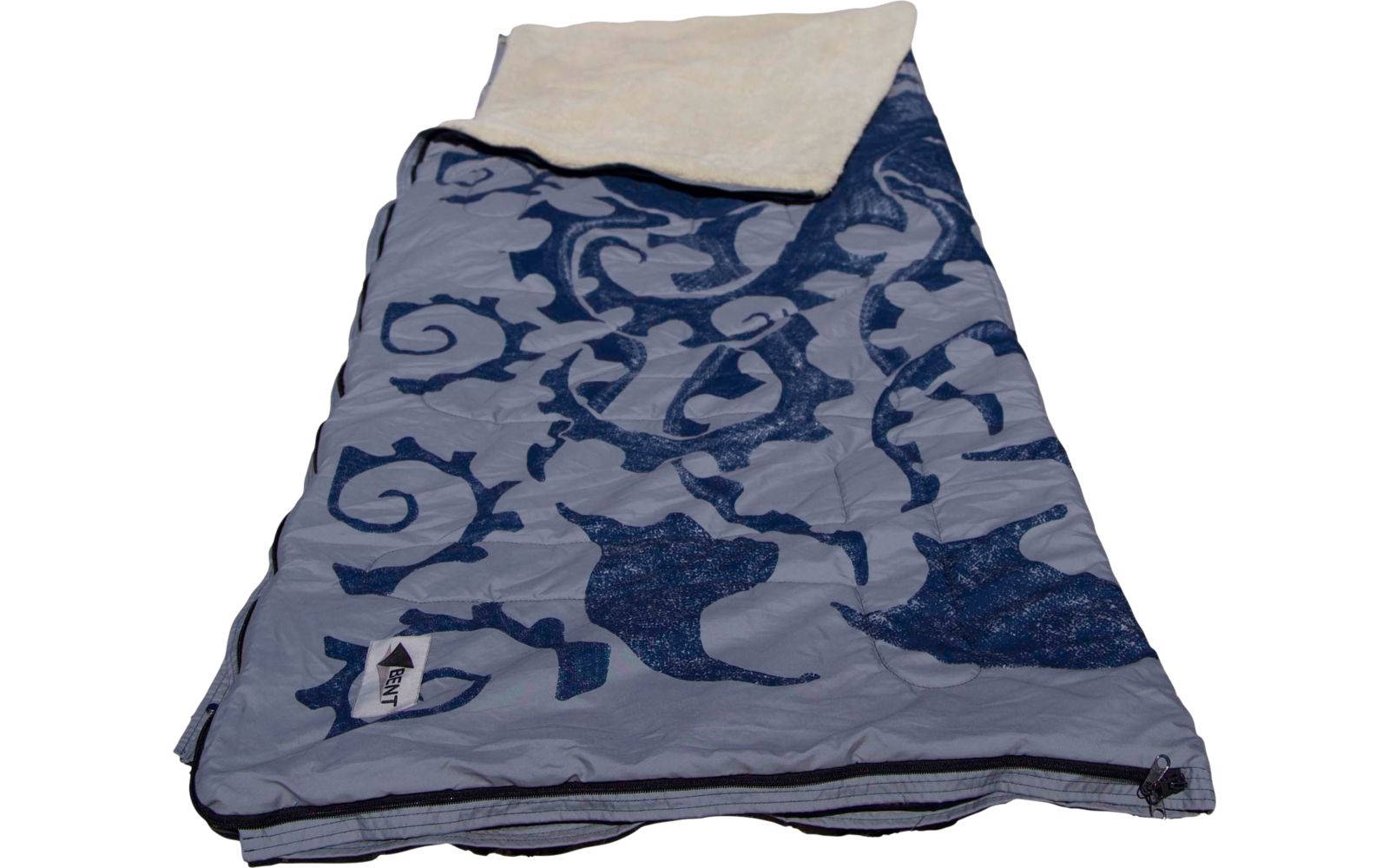 Serviette de plage bleue à motif posée sur du sable clair; herbe de dune, poteaux en bois et ciel bleu en arrière-plan