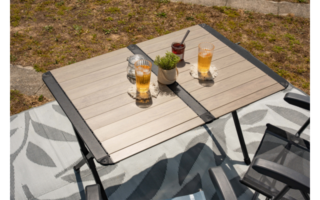 Quadratischer Tisch mit Holzlatten im Freien, zwei hohe Gläser mit Eis, kleine Pflanzenpot, Glasgefäß, Smartphone und zwei Stühle auf gemustertem Teppich