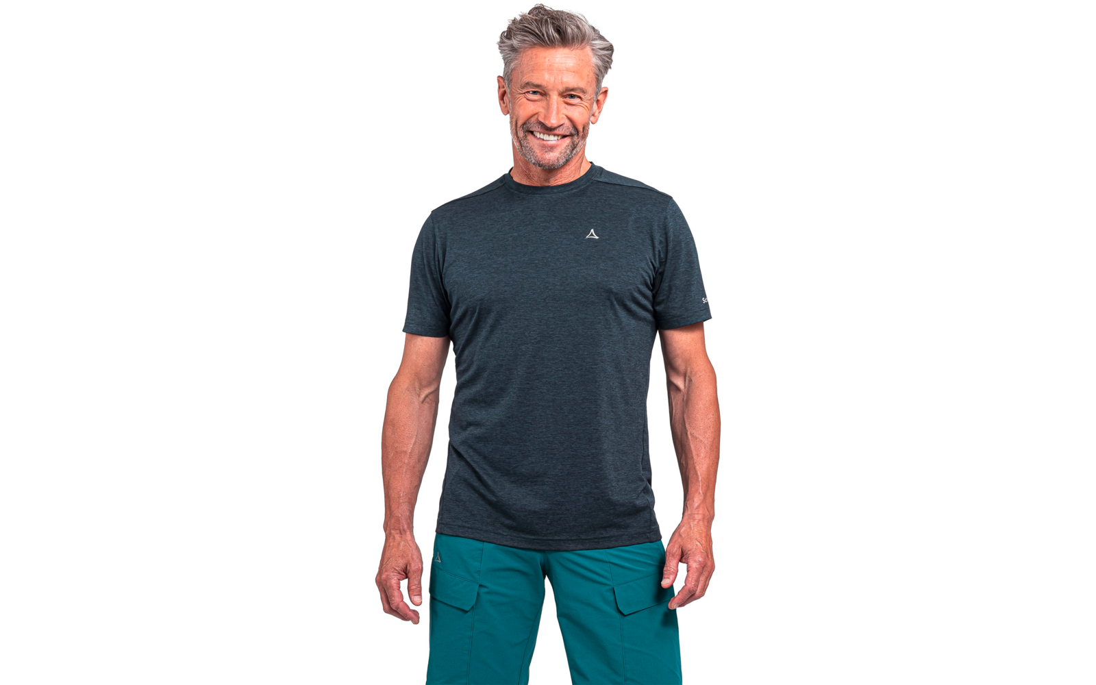 Stehender Mann mit kurzen grauen Haaren, dunkelgrauem T-Shirt mit kleinem Logo auf der Brust und grünen Cargohosen vor weißem Hintergrund