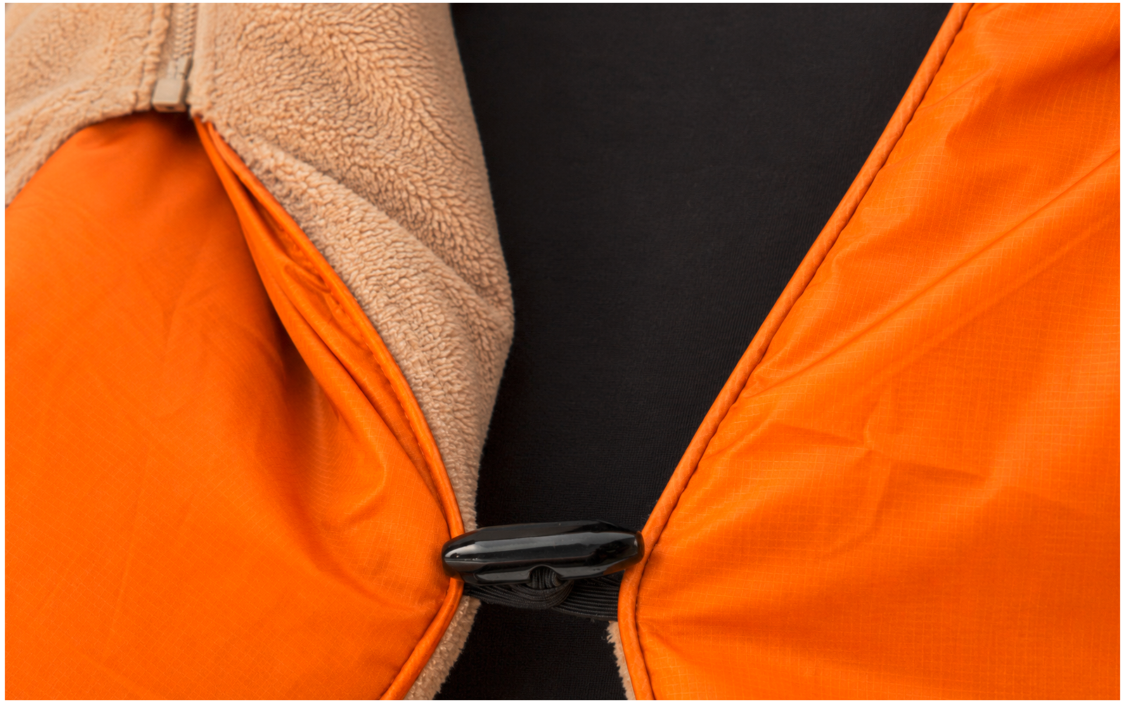 Close-up van een oranje reddingsvest met zwarte gesp en beige fleecevoering