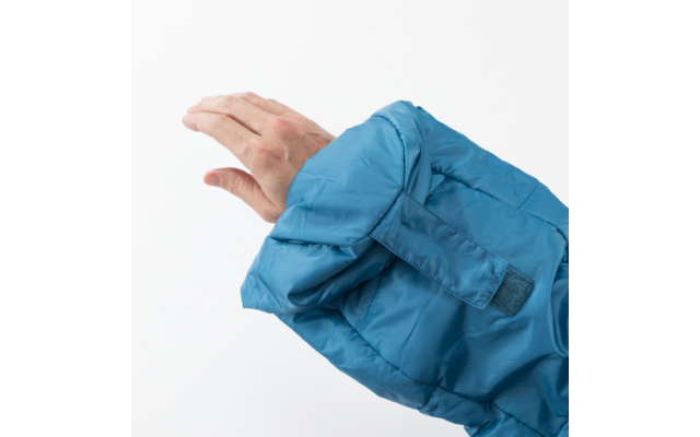 Hand en onderarm deels bedekt door een blauwe gewatteerde jasmouw, witte achtergrond