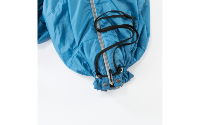 Detailopname van een blauwe jaszoom met rits, zwart koord en metalen oogjes op een witte achtergrond