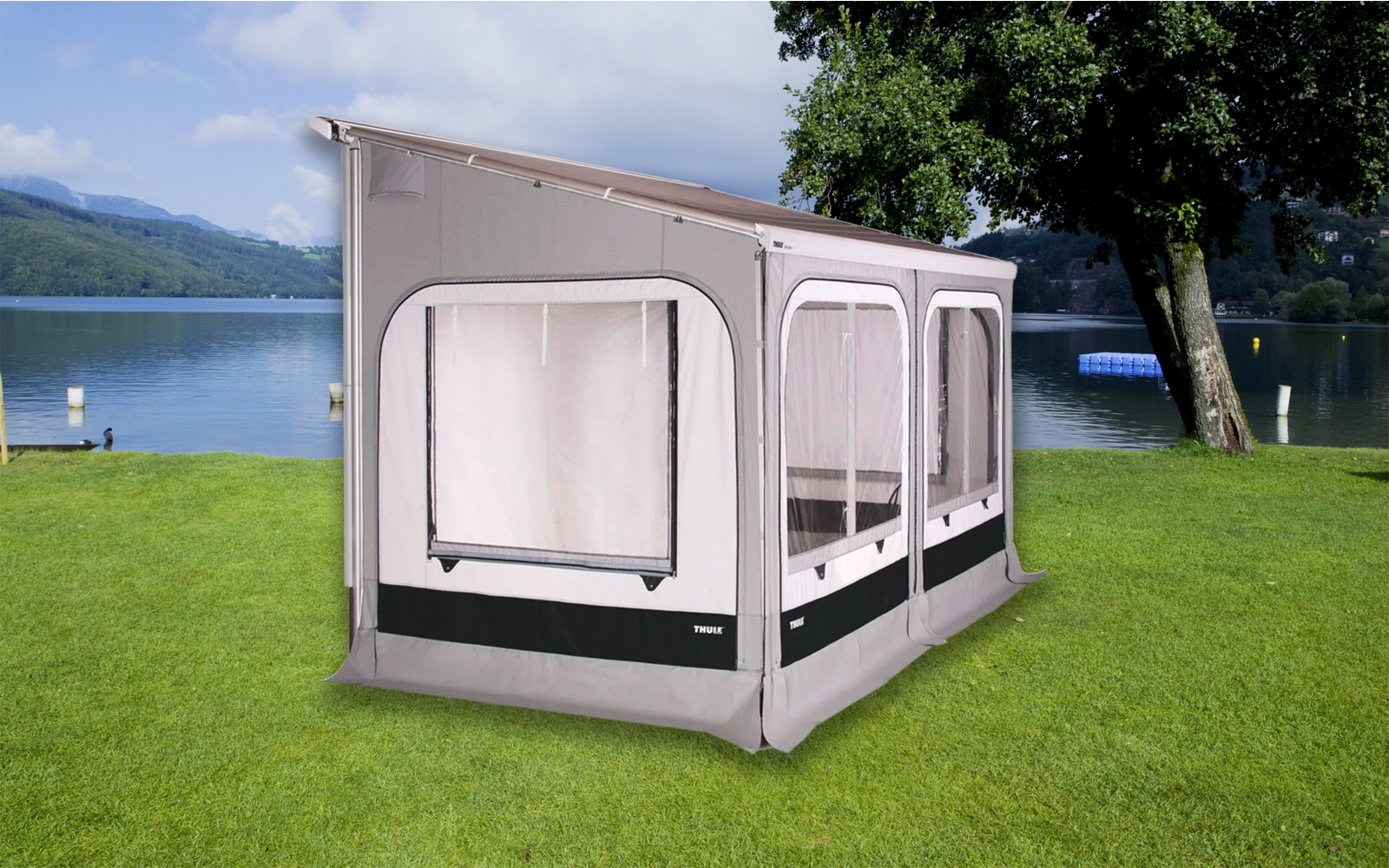 Tenda bianca con grandi finestre su prato verde accanto a un lago e alberi