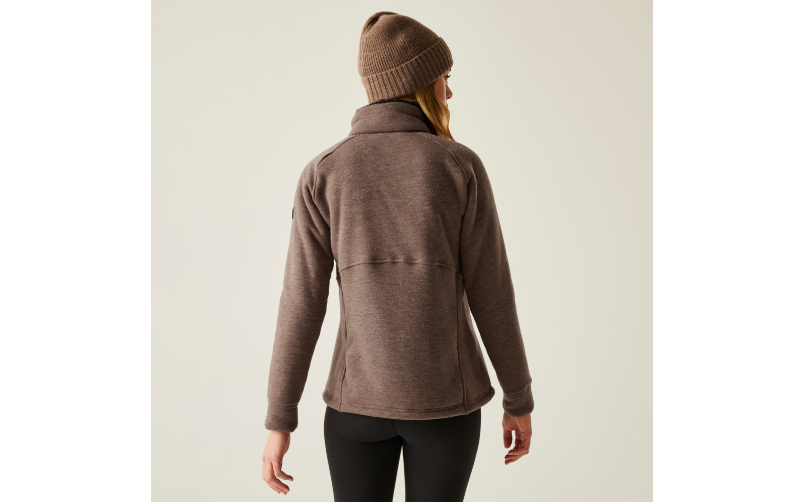 Person von hinten in brauner Jacke und Beanie vor weißem Hintergrund