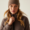 Frau mit beige gestrickter Mütze und braunem Pullover schaut nach vorne