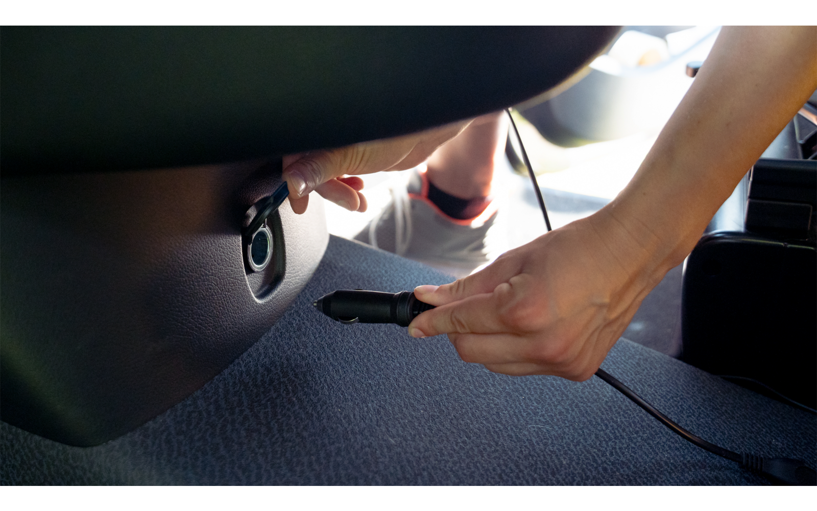 Hand steckt einen USB-Stick in einen Anschluss im Auto