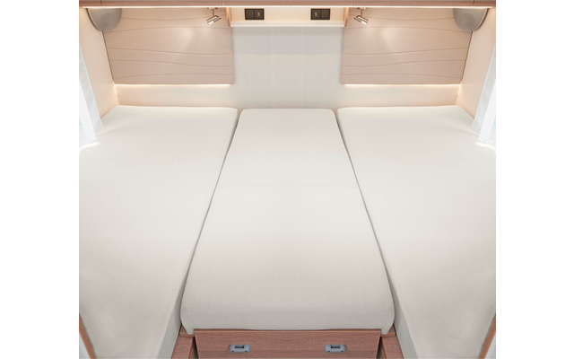 Trois lits simples avec des matelas blancs placés côte à côte dans une pièce lumineuse