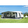 Caravan with awning on green grass under a blue sky