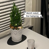 Kleiner grüner Tannenbaum in weißem Topf mit Dekoration auf einem weißen Tisch im Innenraum