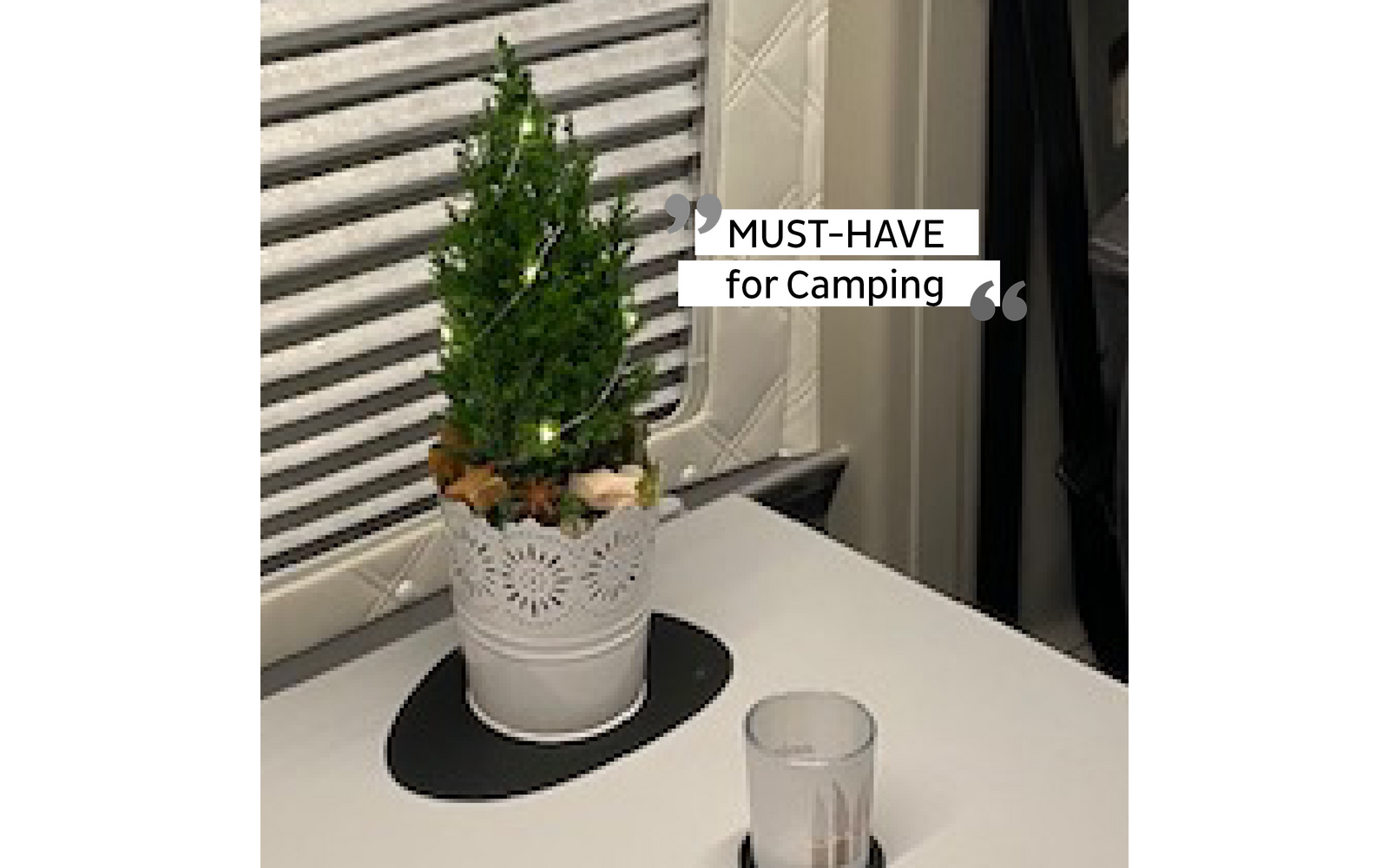 Kleiner grüner Tannenbaum in weißem Topf mit Dekoration auf einem weißen Tisch im Innenraum