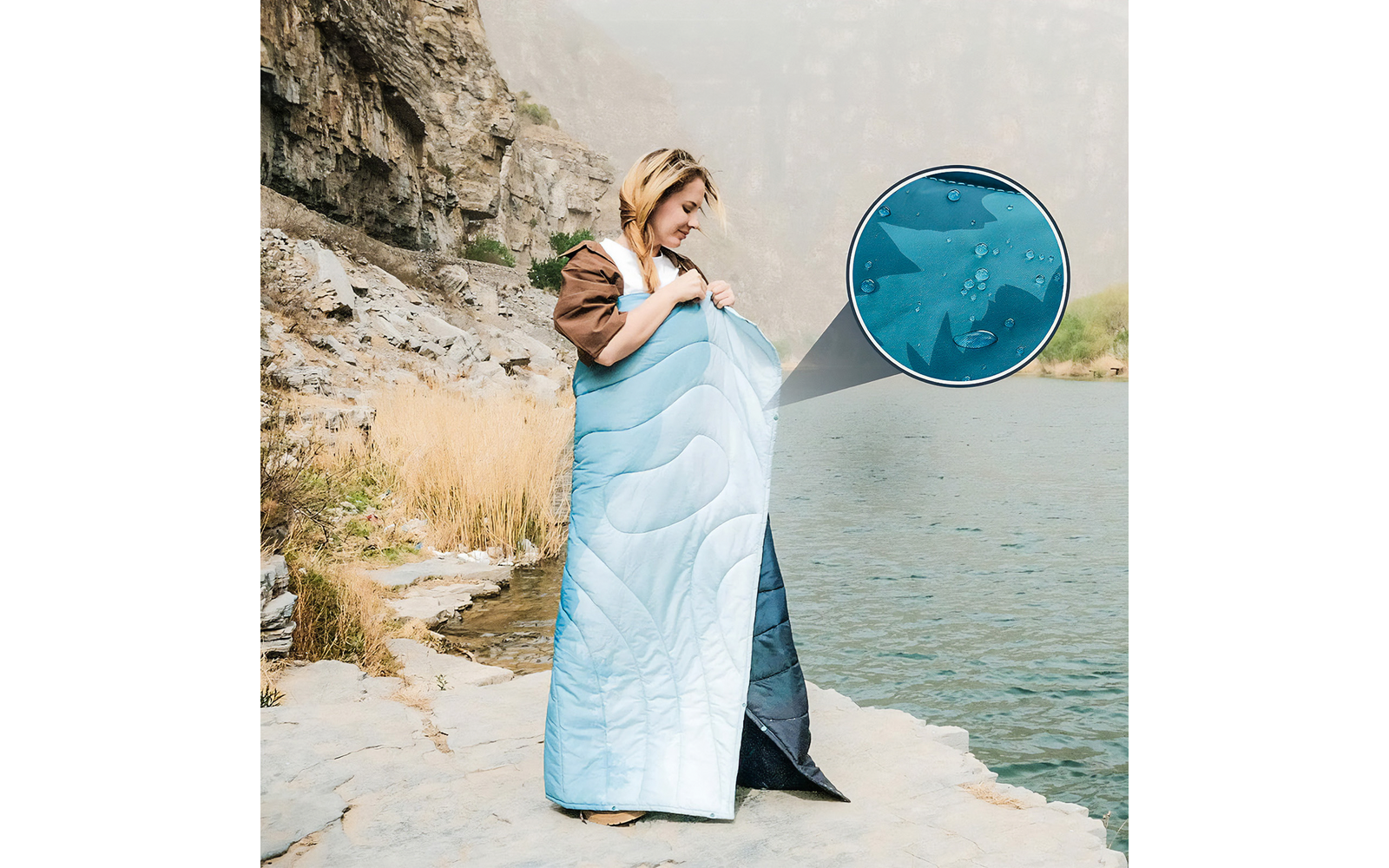 Frau und Kind in einer blauen Decke eingewickelt, stehen am Seeufer neben Felsen