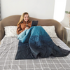 Person sitzt auf einem Bett mit Laptop und Decke