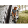 Two people assembling an inflatable tent; one operates a hand pump at the tent, the other adjusts the outer fabric; grass and trees in the background
