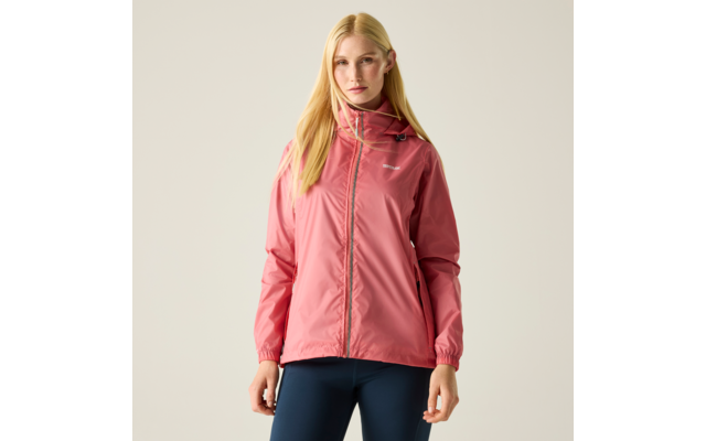 Person steht vor hellem Hintergrund, trägt rosa Kapuzenjacke und dunkle Leggings, lange blonde Haare, Hände seitlich, Blick zur Kamera