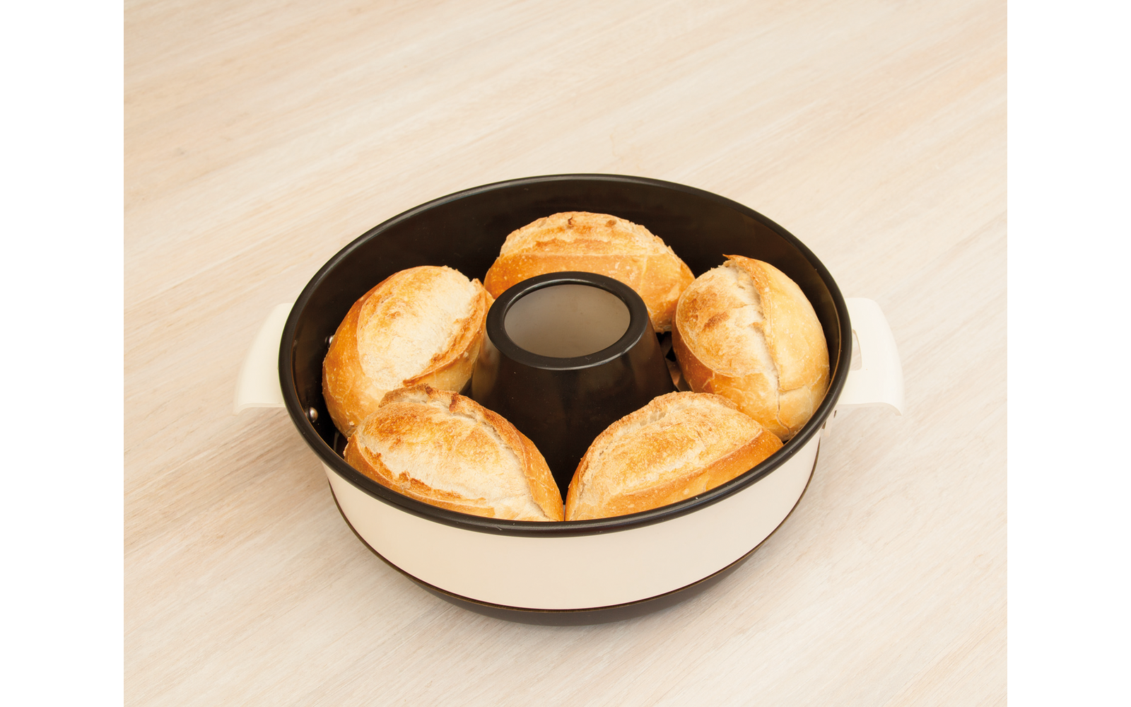 Runder weißer Backring mit schwarzem Innenrand, fünf Brötchen um einen zylindrischen Einsatz angeordnet, auf hellem Holzuntergrund