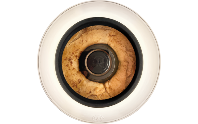 Draufsicht auf einen goldbraunen ringförmigen Kuchen um eine zentrale Metallröhre in einem weißen runden Behälter