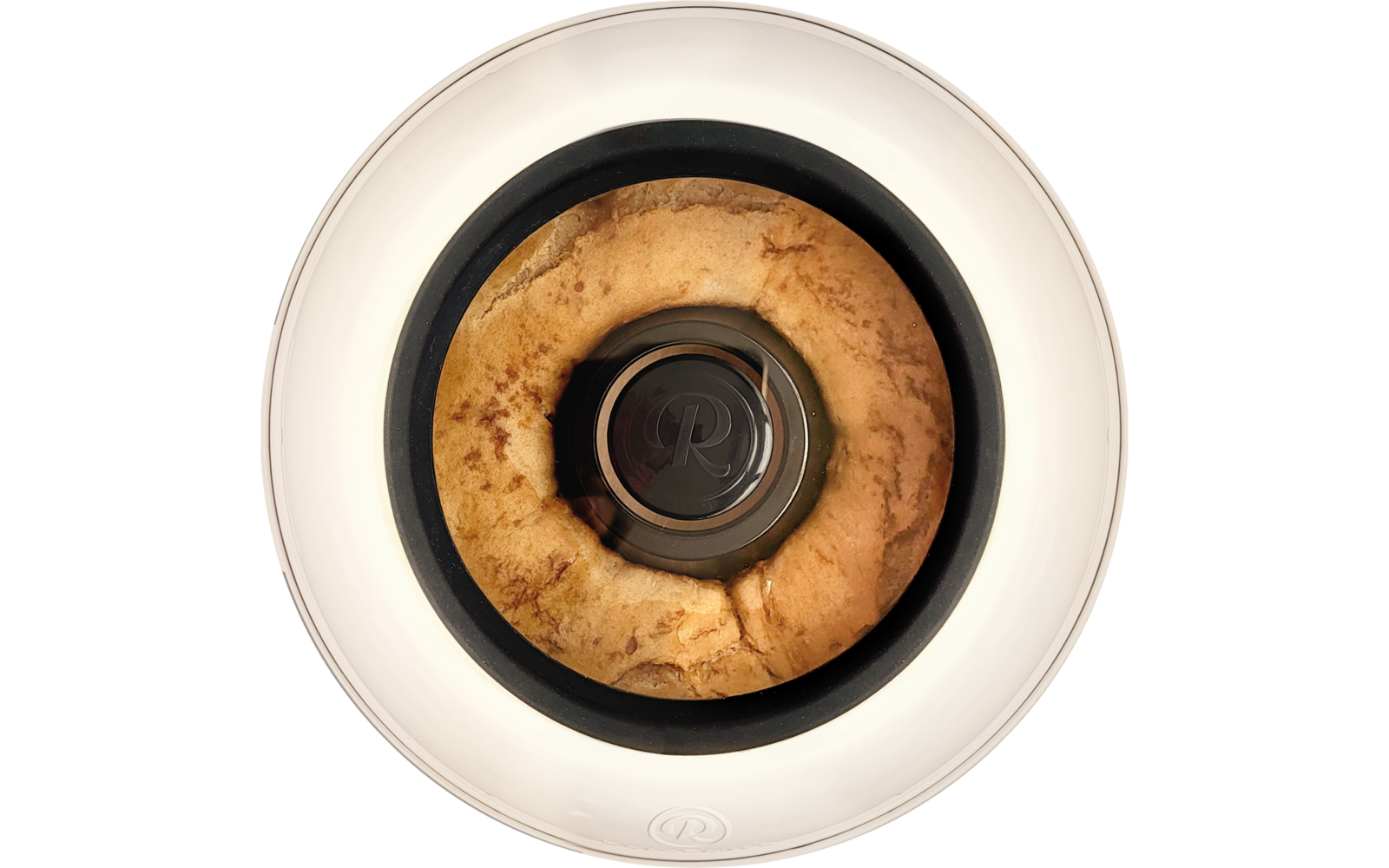 Draufsicht auf einen goldbraunen ringförmigen Kuchen um eine zentrale Metallröhre in einem weißen runden Behälter