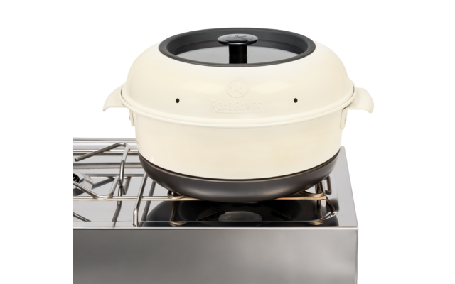 Cremefarbener runder Topf mit schwarzem Deckelknauf auf einem Edelstahl-Gasherd