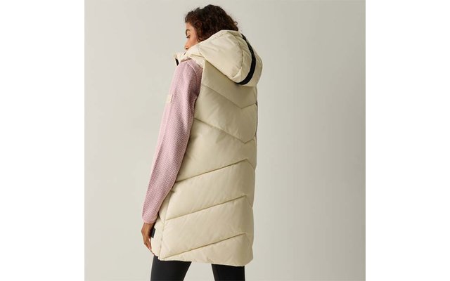 Persona vista di spalle che indossa un lungo gilet trapuntato crema con cappuccio, maglione rosa e leggings neri, sfondo chiaro uniforme