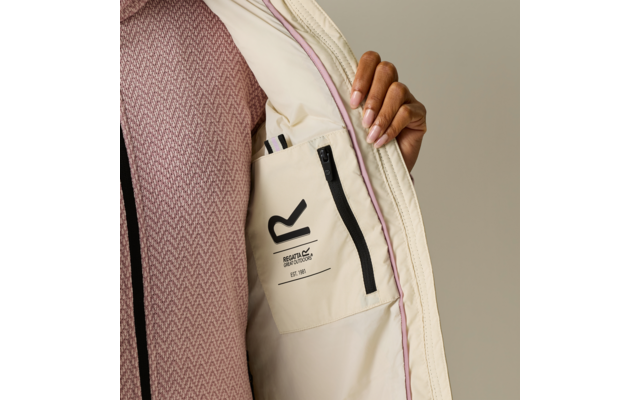 Mano con unghie curate tiene aperta una giacca beige chiaro, fodera interna con tasca interna con zip, logo nero 'R' e piccolo testo sulla tasca, piping rosa, maglione rosa a motivo sotto, sfondo neutro