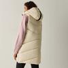 Persona vista di spalle che indossa un lungo gilet trapuntato crema con cappuccio, maglione rosa e leggings neri, sfondo chiaro uniforme