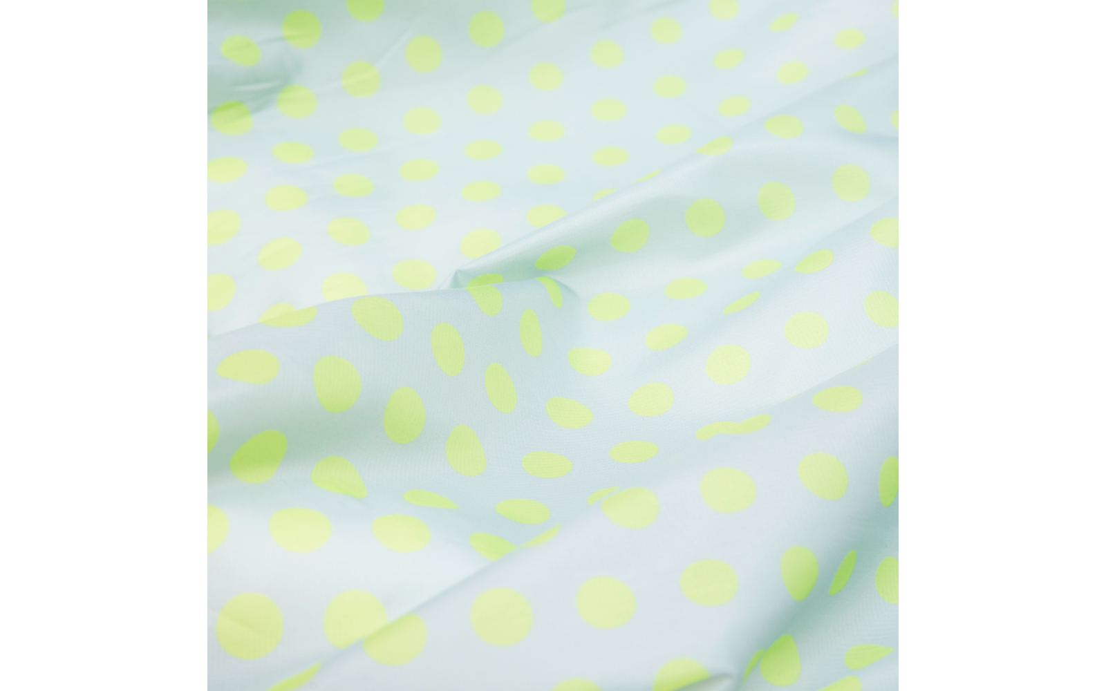 White fabric surface with light green, evenly spaced polka dots and visible folds