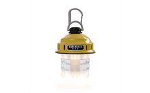 Gelbe Campinglampe mit schwarzem Schraubverschluss, grauem Karabiner oben, BAREBONES-Logo vorn und transparentem, leuchtendem unteren Teil
