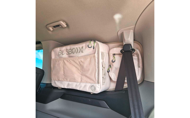 Sac de rangement rectangulaire en tissu clair portant l'inscription "BUSBOXX" avec fermetures éclair, fixé à l'intérieur du véhicule à côté d'une ceinture de sécurité pendante
