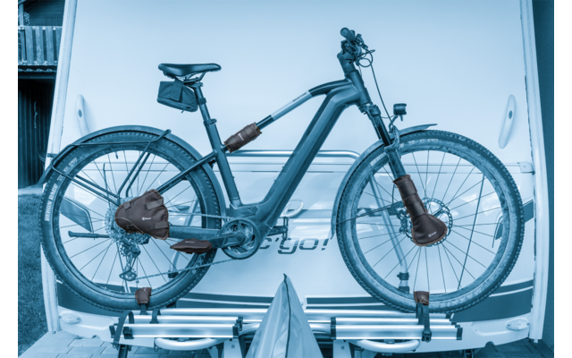 E-Bike mit integrierter Batterie und Satteltasche auf Heckträger eines weißen Fahrzeugs