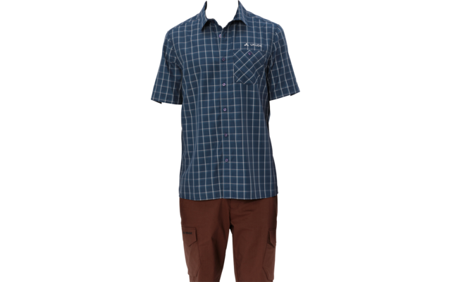 Man standing facing the camera, wearing a blue check short-sleeve shirt with a chest pocket and brown pants, white background