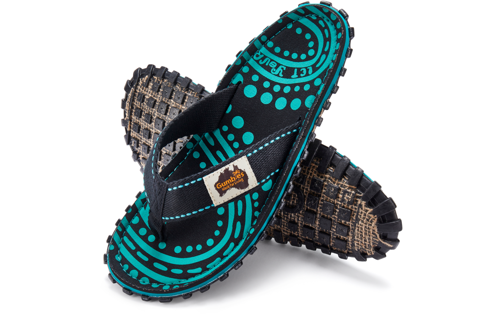 Two overlapping flip-flops with black thong strap, turquoise-and-black dot-and-circle pattern on the footbed, beige brand label on the strap, rugged sole with square tread pattern