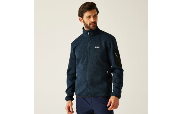 Ein Mann trägt eine dunkelblaue Jacke vor hellem Hintergrund