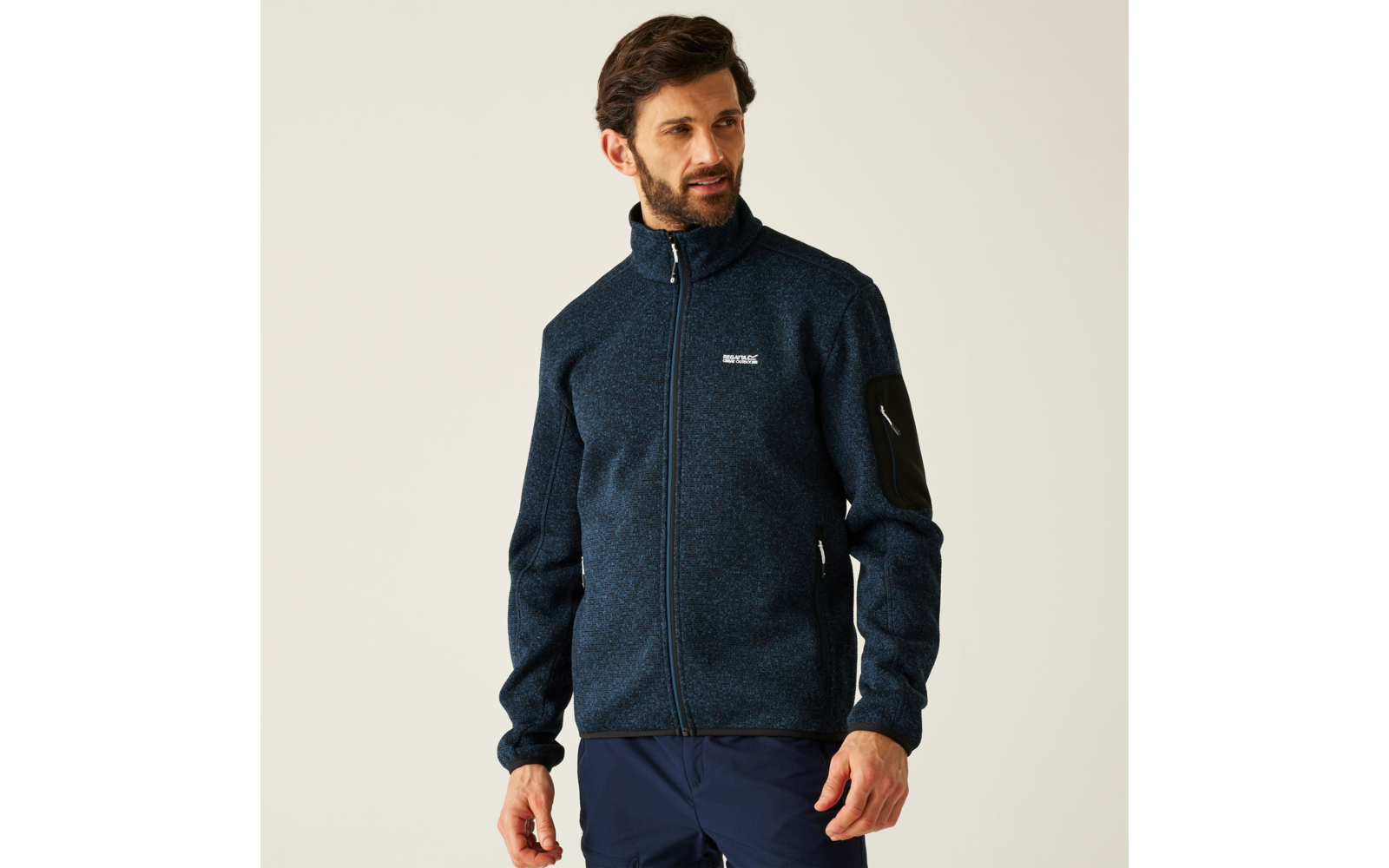 Ein Mann trägt eine dunkelblaue Jacke vor hellem Hintergrund