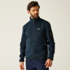Ein Mann trägt eine dunkelblaue Jacke vor hellem Hintergrund
