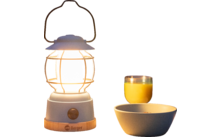 Een brandende lantaarn op een tafel met een kopje, een glas sinaasappelsap en een kom