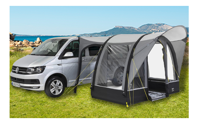 Auto grigia con tenda grigia su erba verde davanti a rocce e cielo blu