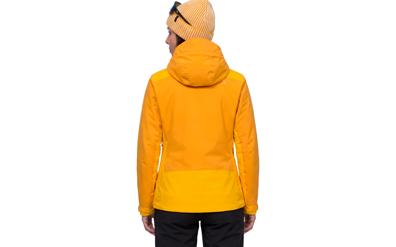 Person von hinten, trägt gelbe Strickmütze mit aufgesetzter Sonnenbrille, gelb-orange Jacke mit Kapuze und schwarze Hose