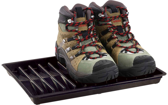 Une paire de chaussures de randonnée brun-vert avec lacets rouges sur un bac à chaussures en plastique noir sur fond blanc