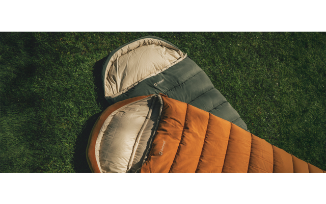 Twee open slaapzakken, één oranje en één olijfgroen, naast elkaar op gras, bovenaanzicht