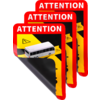 Drei überlappende rechteckige Aufkleber mit rotem Rand, weißer Schrift 'ATTENTION' oben, gelb-schwarzen diagonalen Streifen, kleinem weißem Bus-Piktogramm und nach oben geklappter unterer Ecke