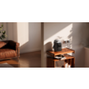 Innenraum mit braunem Ledersofa links, Holzboden, hölzerner Beistelltisch/Regal mit Kaffeemaschine, Steckdose an der Wand, Sonnenlicht und Schatten auf der Wand