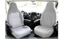 Twee grijze autostoelen in een voertuig met armleuningen en uitzicht door de voorruit