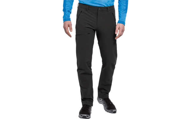 Vista parcial de una persona de pie desde la cintura hasta los pies con pantalones outdoor negros con bolsillos con cremallera, una prenda de manga larga azul y zapatos de senderismo negros