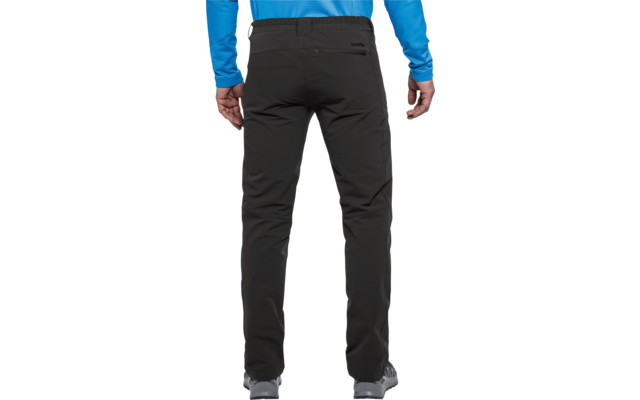 Vista trasera de una persona de pie que viste pantalones largos negros, una prenda superior azul claro y zapatos grises; manos a los lados, bolsillos traseros visibles